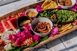 Colorful display of Tanzanian food on a boat-shaped platter adorned with flowers.